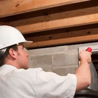 Termite inspection technician checking a basement wall and framing for termite activity in Des Moines, IA